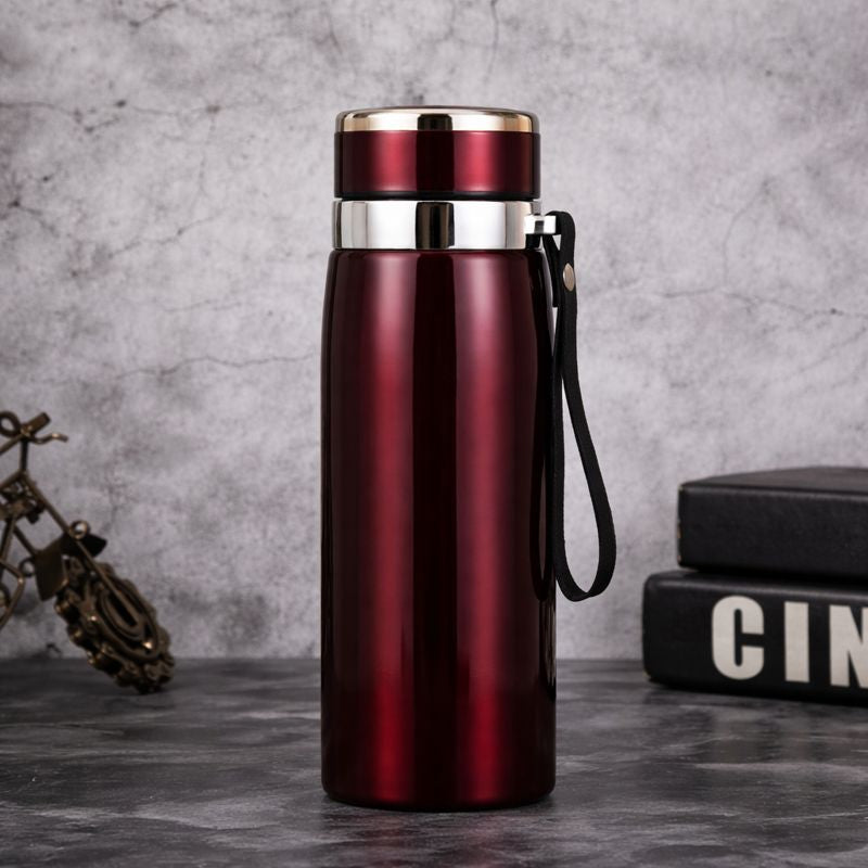 Red insulated bottle with a silver lid on a gray surface