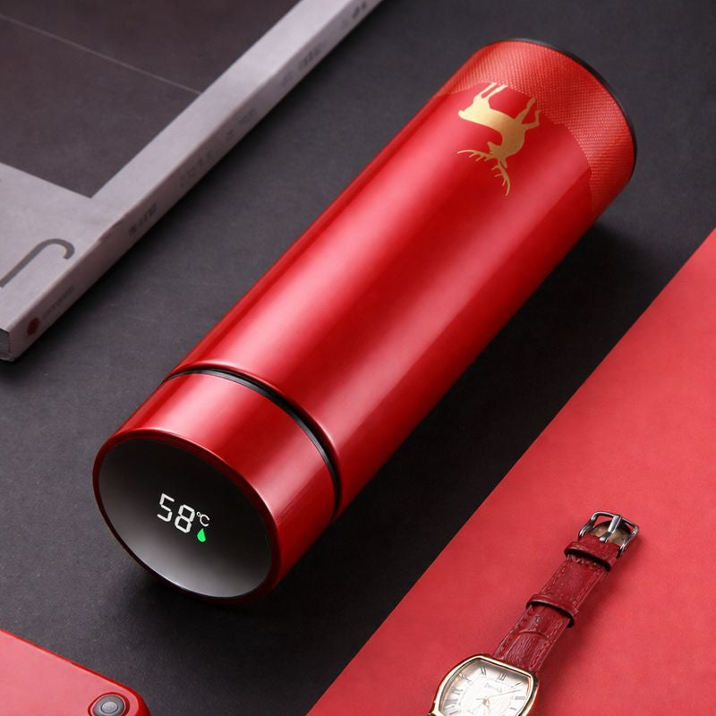 Red thermos with digital temperature display on a dark surface with a watch and phone.