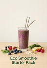 Glass of smoothie with straws, berries, and fruits on a wooden surface with 